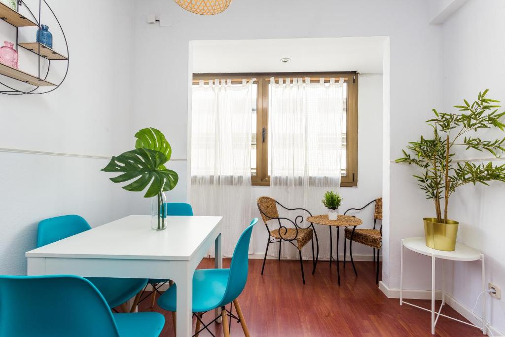a dining room with a white table and blue chairs at Lodging Apartments Illa Diagonal in Barcelona