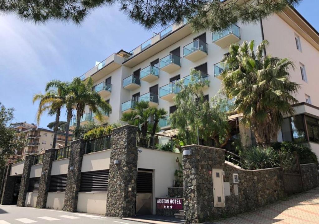 ein Gebäude mit Palmen davor in der Unterkunft Hotel Ariston & Apartments in Varraze