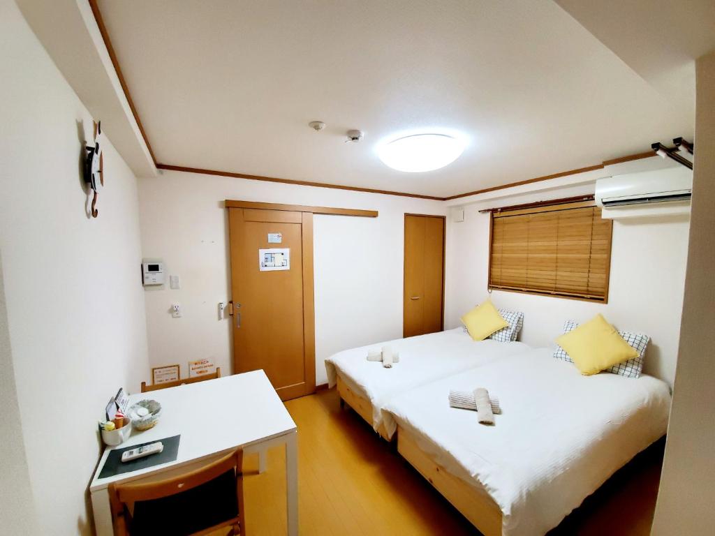a hotel room with two beds and a desk at Takaraboshi room 201 Sannomiya 10 min in Kobe