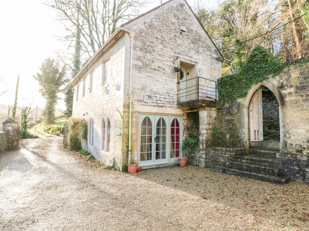 an old stone house with a balcony on a dirt road at Chapel Cottage in Stroud