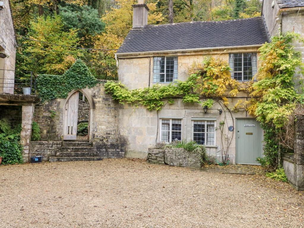 an old stone house with a driveway in front of it at October Cottage in Stroud