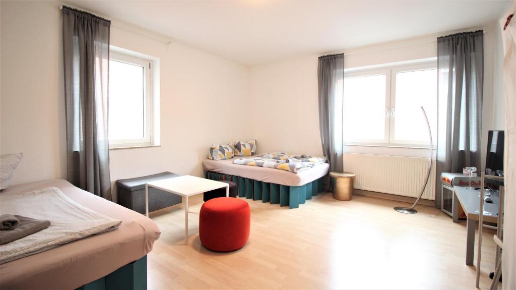 Habitación pequeña con 2 camas y taburete rojo. en City Room near main station, bycicle cellar, en Würzburg
