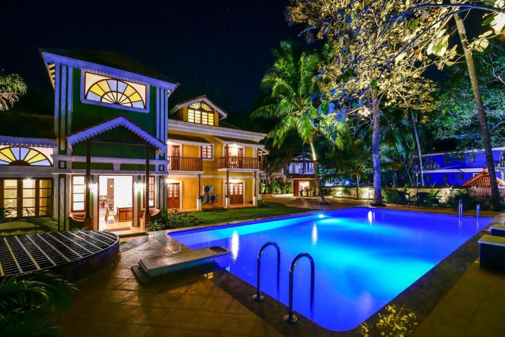 a swimming pool in front of a house at night at The Amrit Goa in Candolim