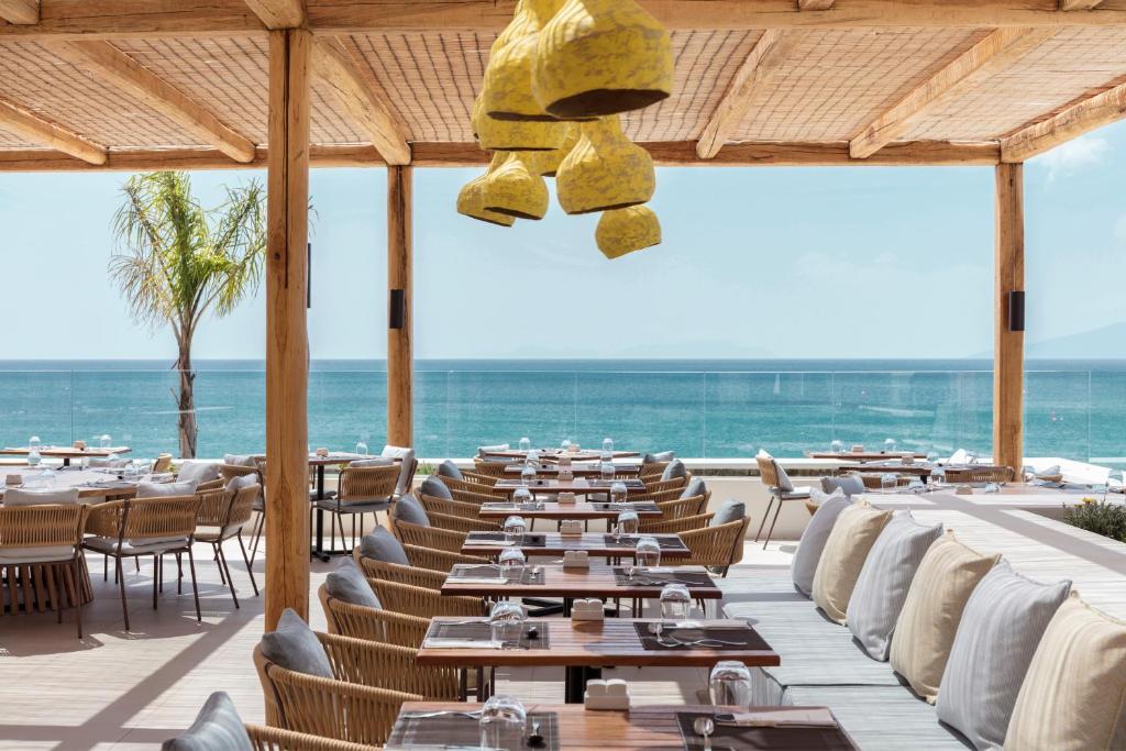 a restaurant with tables and chairs and the ocean at Mitsis Norida in Kardamaina