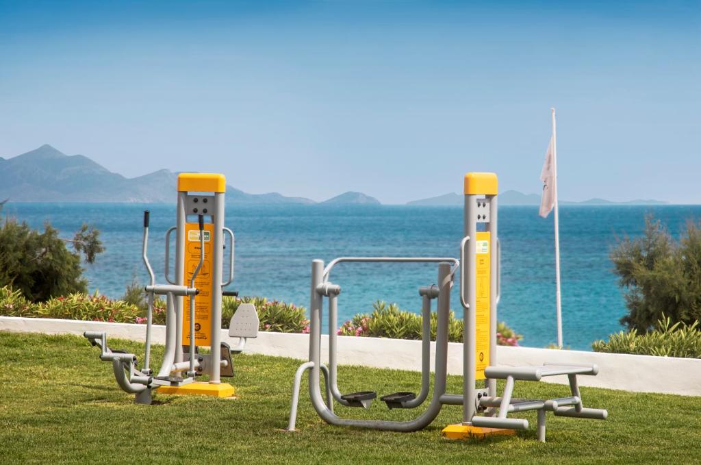 a row of exercise equipment on the grass near the water at Mitsis Norida in Kardamaina