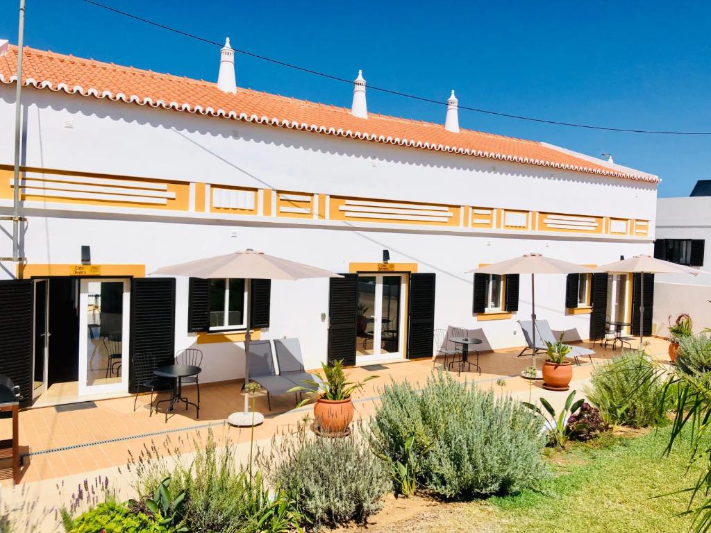 a white building with chairs and umbrellas in a yard at Quinta David in Alvor