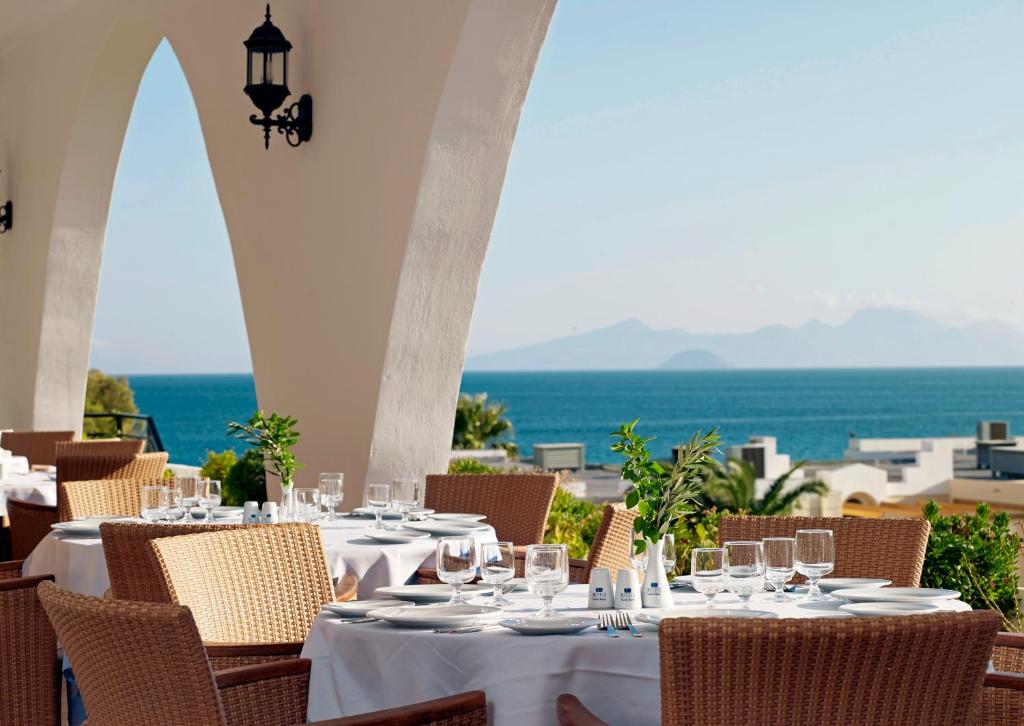 a table with wine glasses and a view of the ocean at Mitsis Norida in Kardamaina