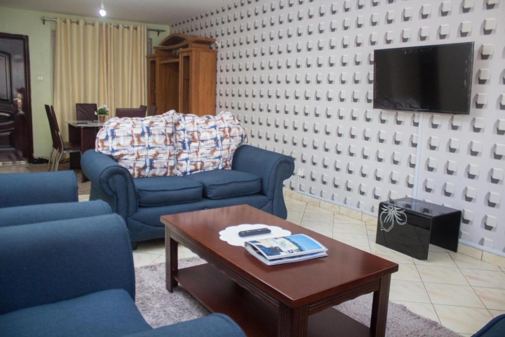 uma sala de estar com duas cadeiras azuis e uma mesa de centro em Essy's Apartments Nakuru with pool & GYM em Nakuru