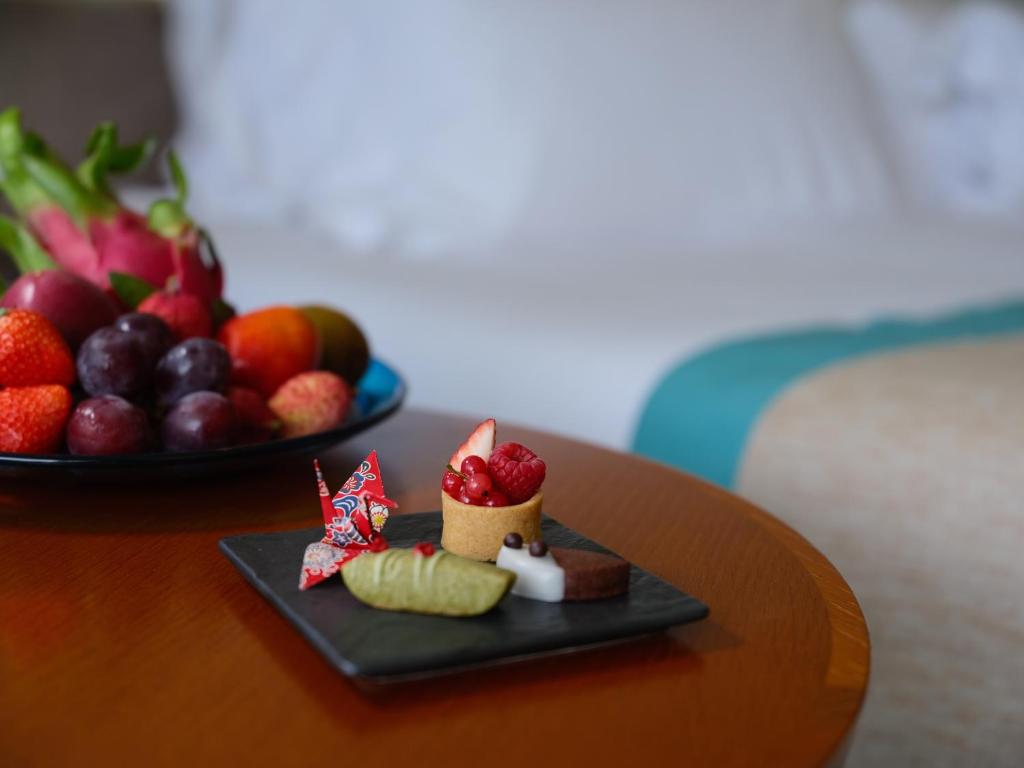 a plate of food on a table with a bowl of fruit at ANA InterContinental Manza Beach Resort by IHG in Onna