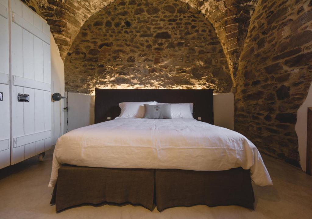 a bedroom with a large bed in a brick wall at Torre di Baratti Bio Resort in Populonia
