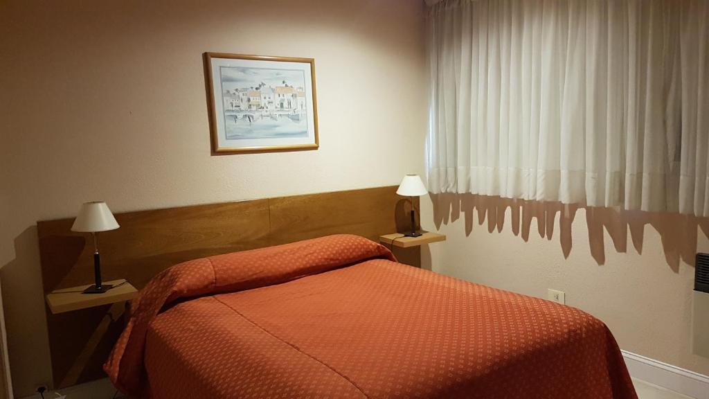 a bedroom with a bed with an orange bedspread and a window at Maison Apart Hotel in Mar del Plata