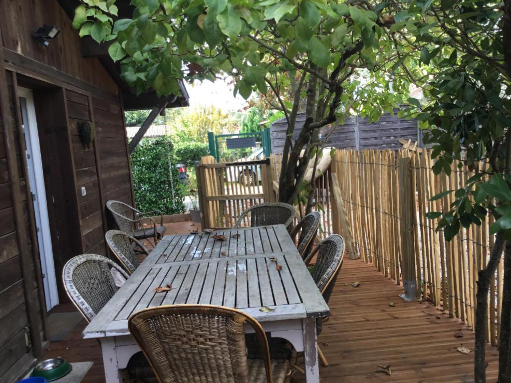 einen Holztisch und Stühle auf einer Terrasse in der Unterkunft Charmant T3 à proximité du Bassin in Arès
