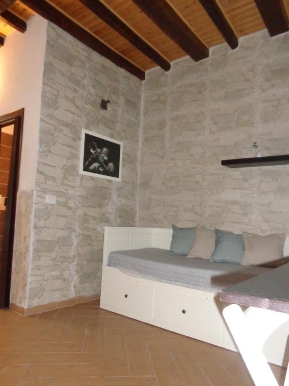 a bed in a room with a stone wall at Casa Gaia Ortigia Holiday Home in Syracuse