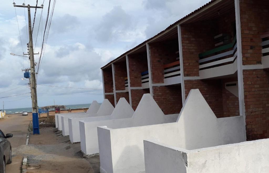 a brick building with white fences on the side of it at Casa na Ilha da Croa in Barra de Santo Antônio