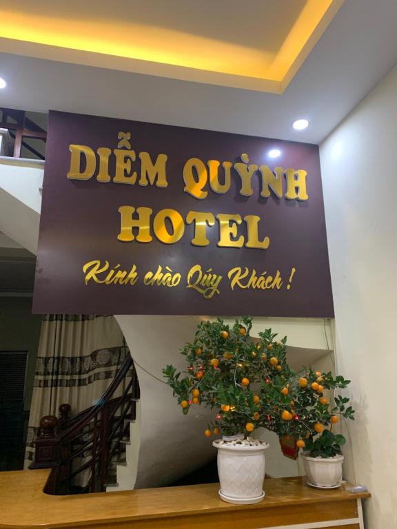 un letrero para un hotel con un naranjo en Nhà Nghỉ Diễm Quỳnh, en Noi Bai