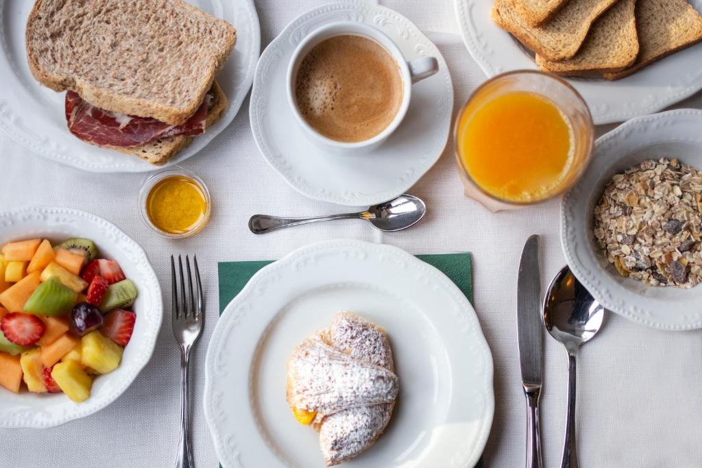 - une table avec des assiettes de produits pour le petit-déjeuner et une tasse de café dans l'établissement Hotel Estense, à Modène