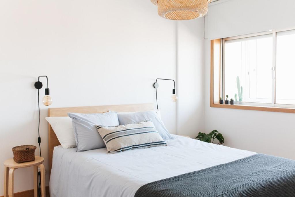 Un dormitorio con una cama con paredes blancas y una ventana en Cozy Panoramic Apartment near Metro Station, en Senhora da Hora
