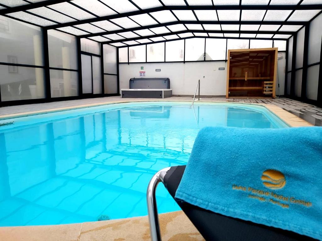 una piscina con una toalla azul en una silla en Milfontes Guest House - Duna Parque Group, en Vila Nova de Milfontes
