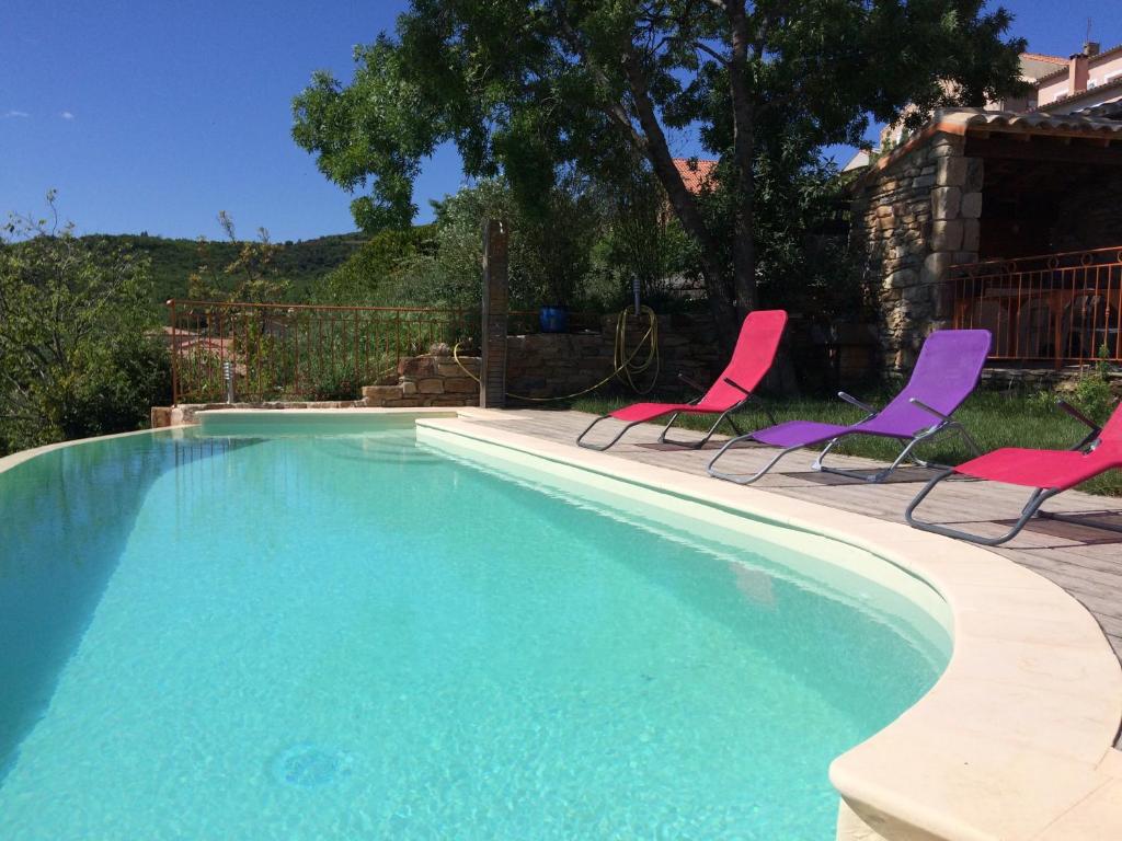a swimming pool with two chairs and a swimming pool at Lestival, le gîte in Usclas-du-Bosc