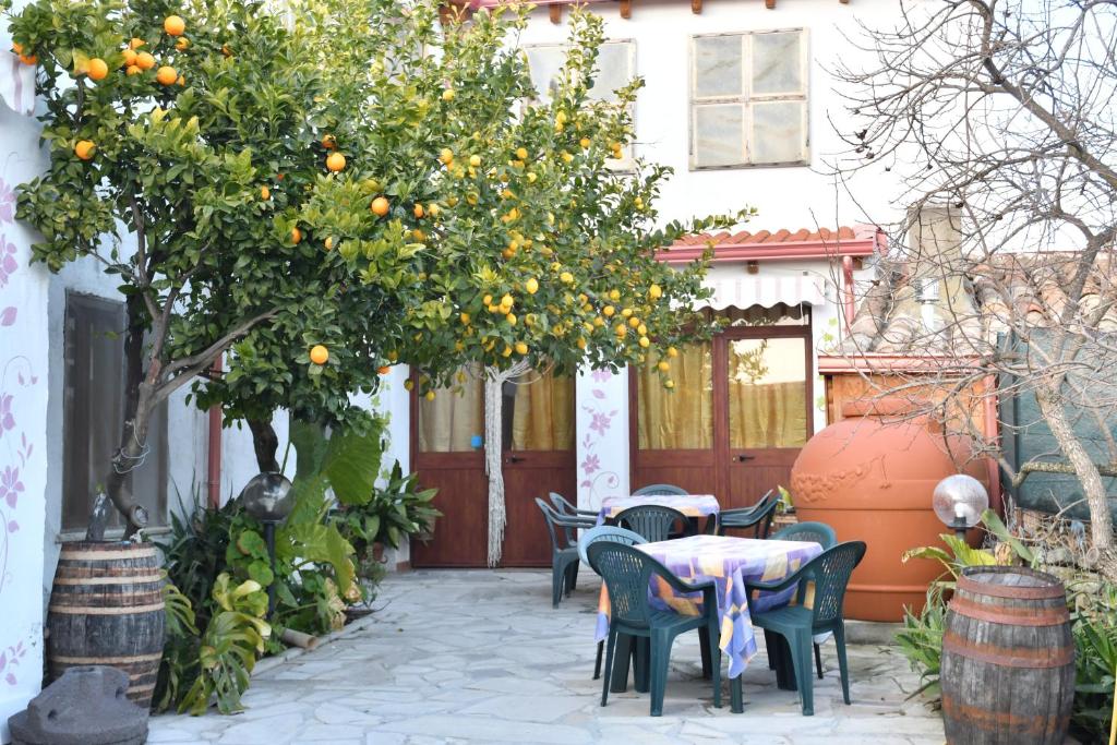 a patio with a table and chairs under an orange tree at B&B Mitzixeddas Sa Domu de Braxia in Màndas