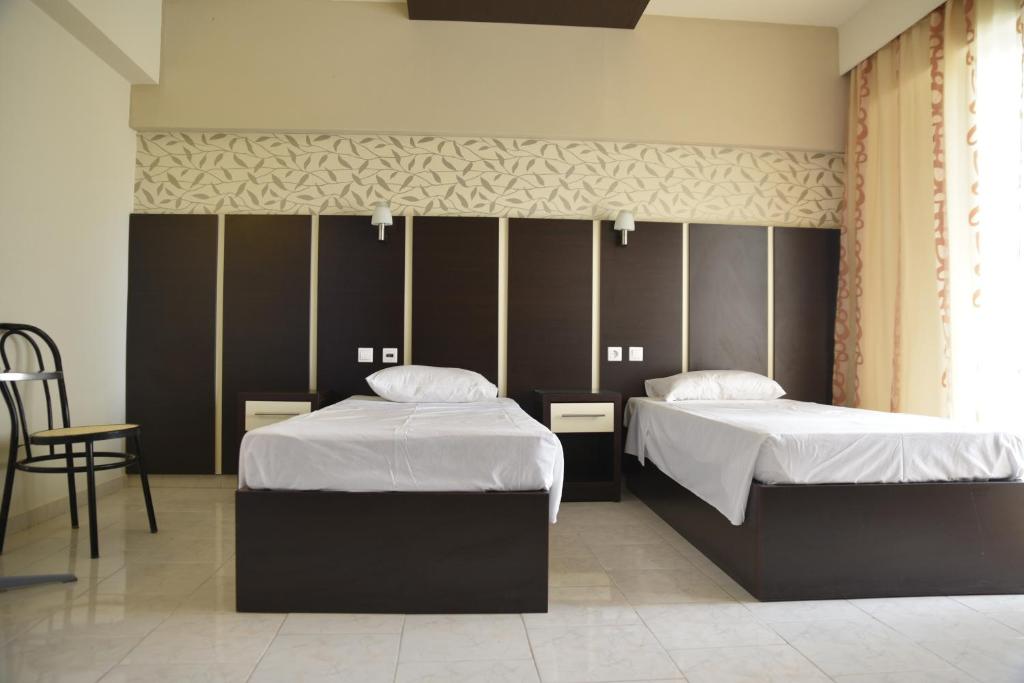 a bedroom with two beds and a chair at Rose Hotel Faliraki in Faliraki