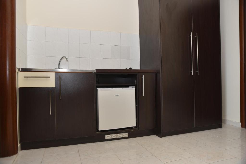 a kitchen with brown cabinets and a white dishwasher at Rose Hotel Faliraki in Faliraki
