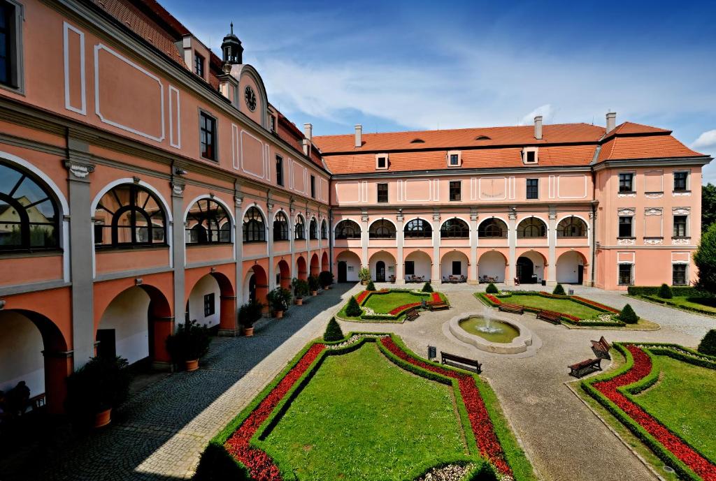 a courtyard with a large building and a garden at Zámecký Penzion in Valašské Meziříčí