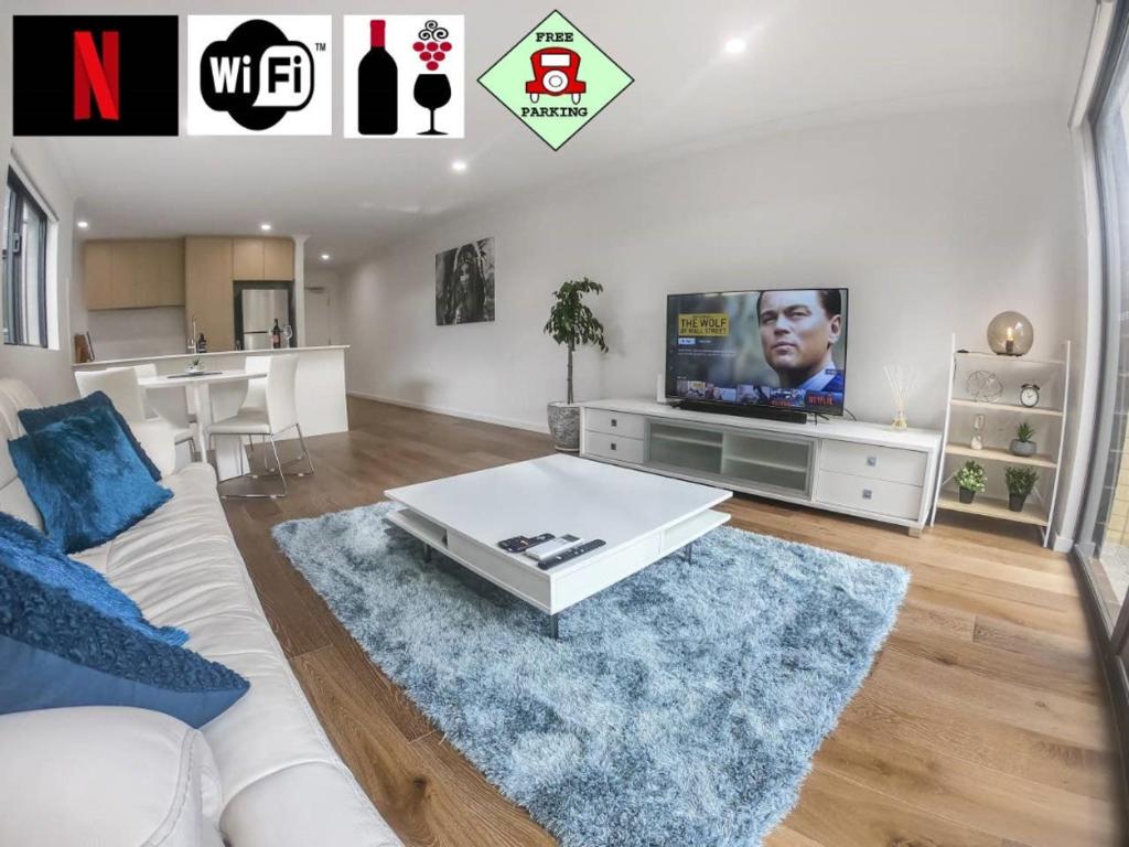 sala de estar con sofá blanco y TV en 1 Bdrm Close Airport/Shops, WIFI, NETFLIX, PARKING, en Perth