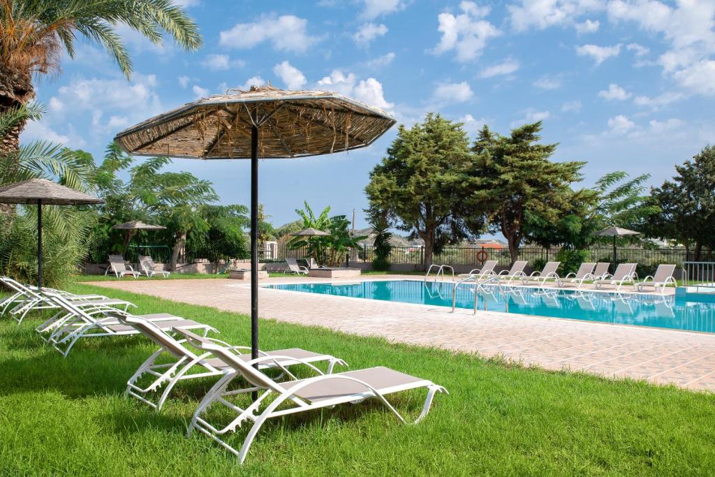 a group of chairs and an umbrella next to a pool at Rose Hotel Faliraki in Faliraki