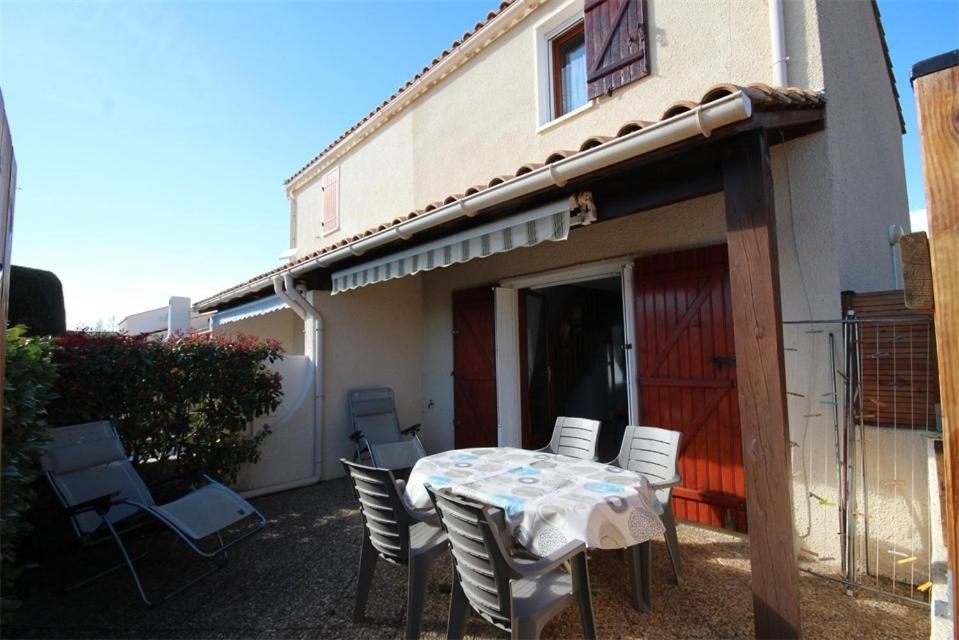 uma mesa e cadeiras em frente a uma casa em Villa d'angle, 5 couchages, 2 chambres etage, terrasse Sud parking dans résidence sécurisée, WIFI , piscine commune 400m de la mer LRJP123 em Portiragnes