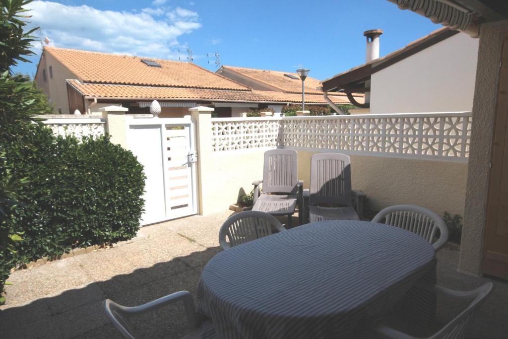 un patio avec une table et des chaises et une clôture dans l'établissement villa d'angle 4 couchages terrasse ombragée parking dans résidence sécurisée piscine commune 400m de la mer LRJP78, à Portiragnes