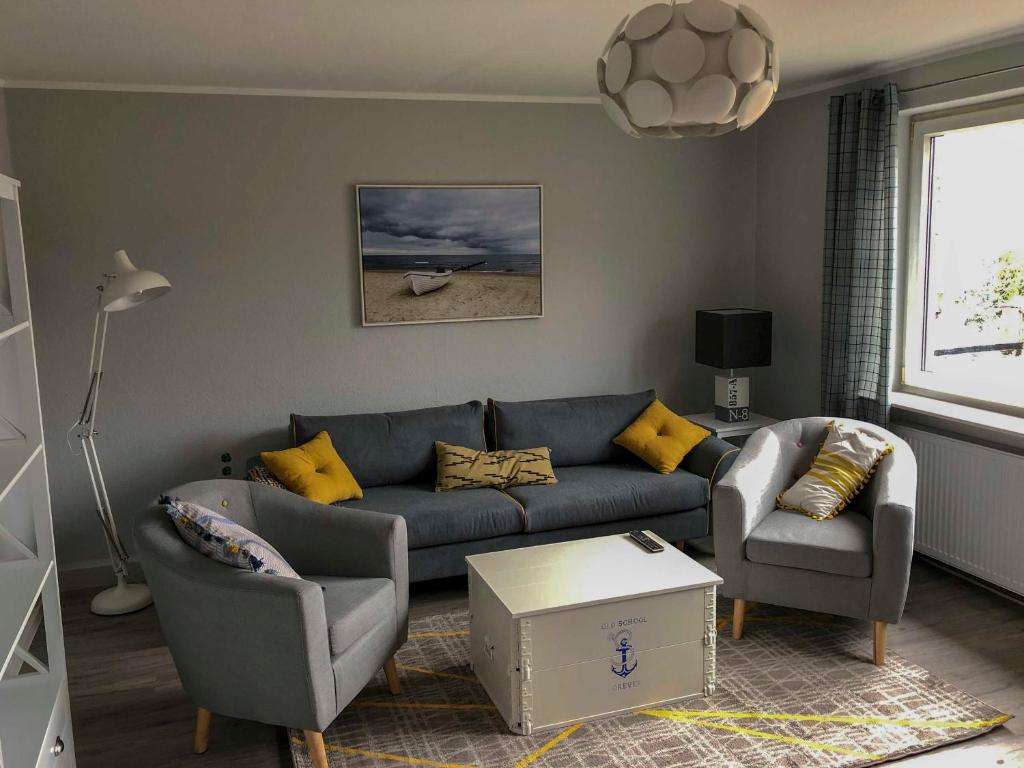 sala de estar con sofá azul y 2 sillas en 168 Salzwiese Ferienwohnung, en Accumersiel