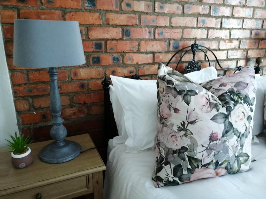 a bed with a pillow and a lamp on a night stand at LemonBlossom in Bloemfontein