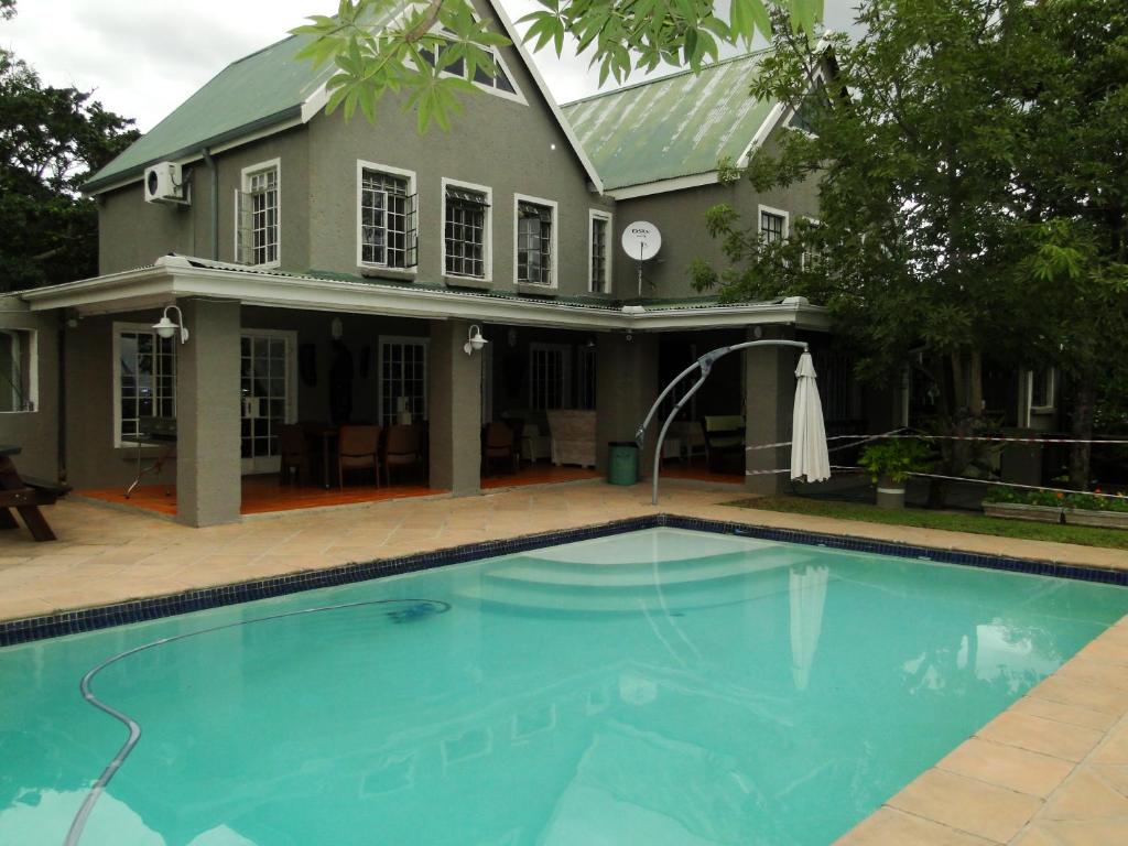 a swimming pool in front of a house at Highlands Creek Self Catering Accommodation in Nelspruit