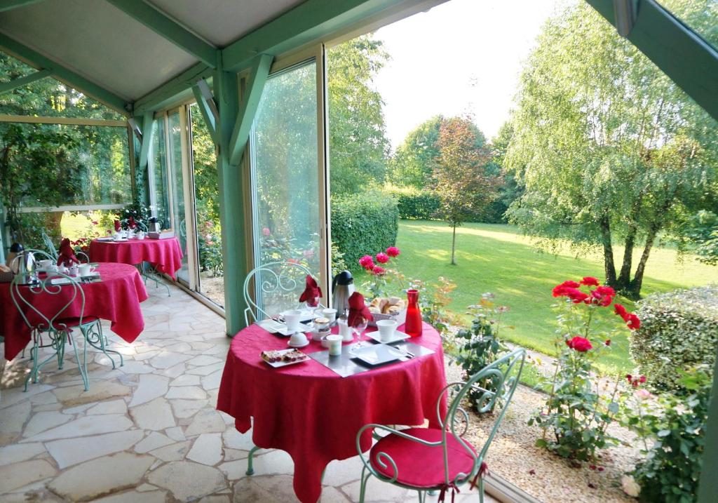 um conservatório com duas mesas com toalha de mesa vermelha em Les Feuillantines Perigord Noir em Saint-Cyprien