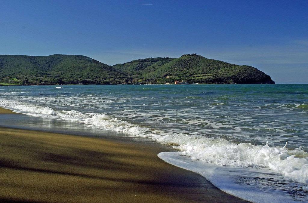a view of the beach with a mountain in the background at Torre di Baratti Bio Resort in Populonia
