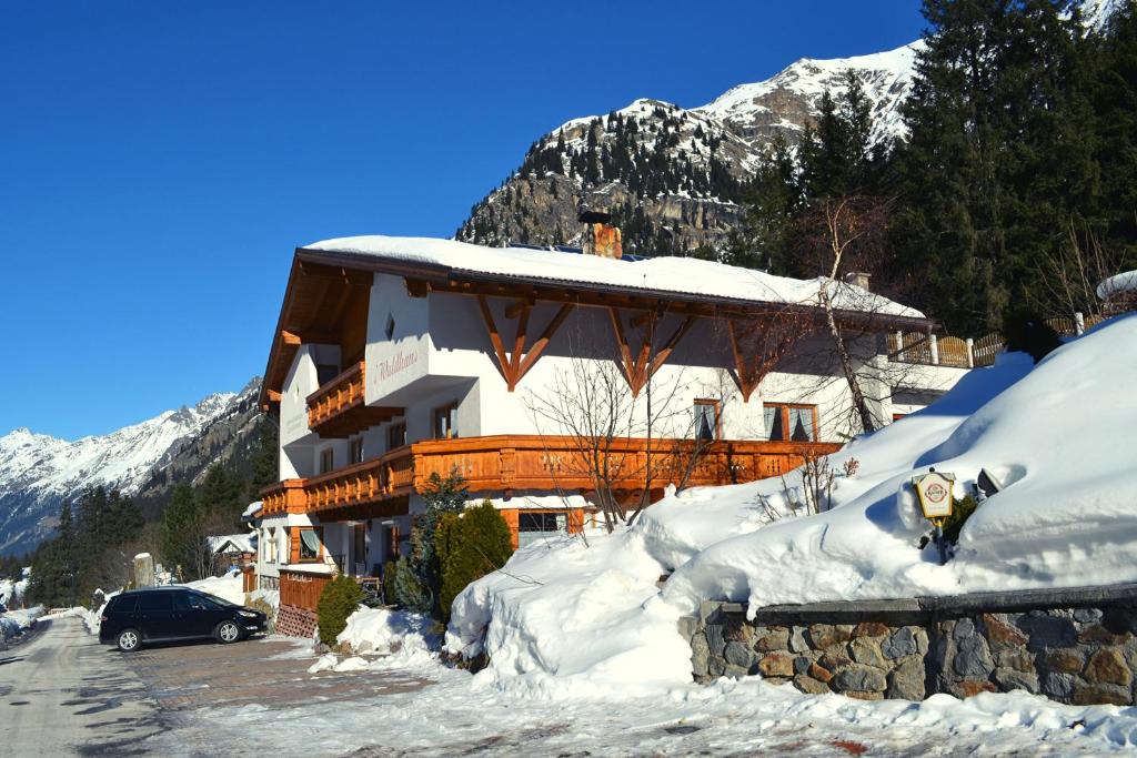 un edificio cubierto de nieve con un coche aparcado delante en s´Waldhaus, en Sankt Leonhard im Pitztal