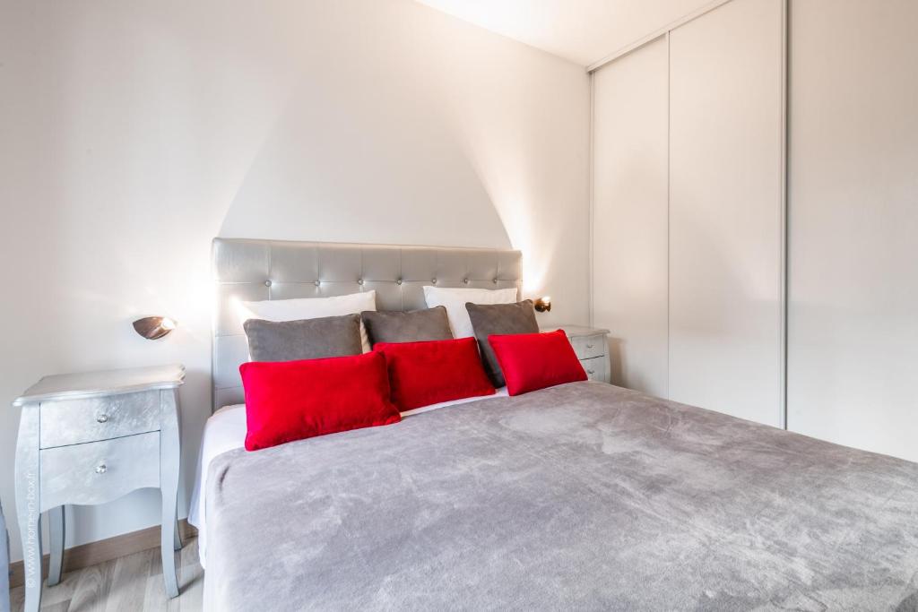 a white bedroom with a large bed with red pillows at EDEN PARK LUXE DISNEY in Montévrain