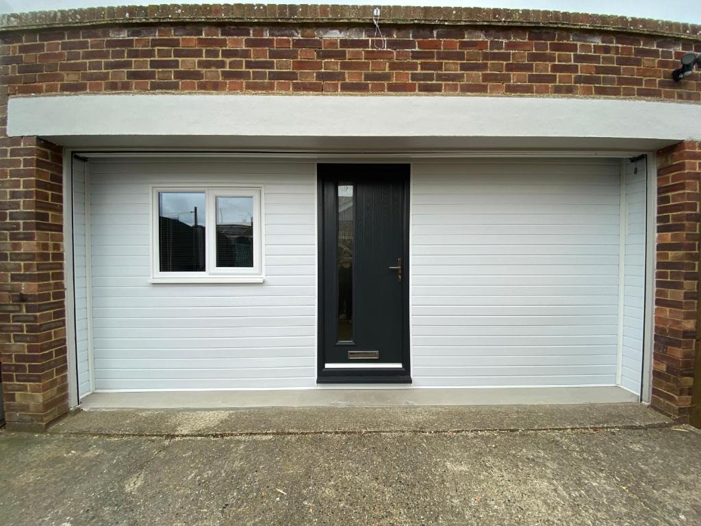 a white garage door with a window in a brick building at Margate Seaside Retreat in Margate
