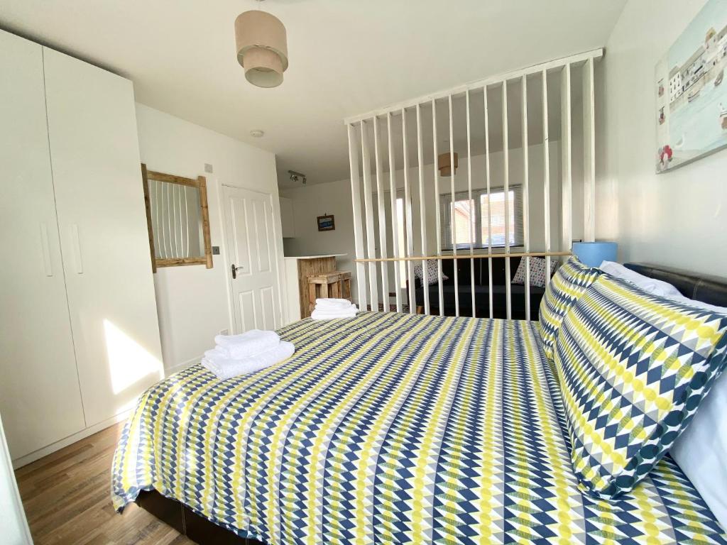 Schlafzimmer mit einem Bett mit gelber und blauer gestreifter Bettwäsche in der Unterkunft Margate Seaside Retreat in Margate