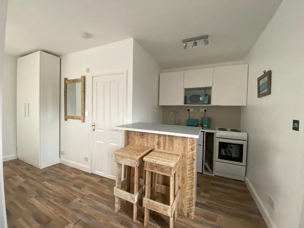 a kitchen with white cabinets and a counter with stools at Margate Seaside Retreat in Margate