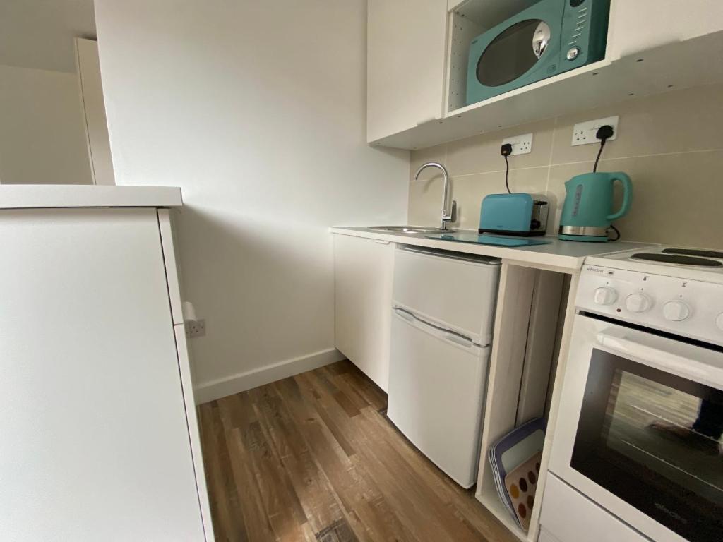 a small kitchen with white cabinets and a stove at Margate Seaside Retreat in Margate