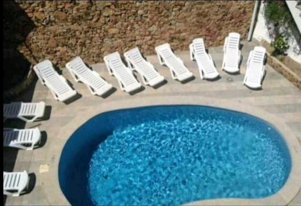 a group of white chairs and a blue pool at Apartamento Blanes in Blanes