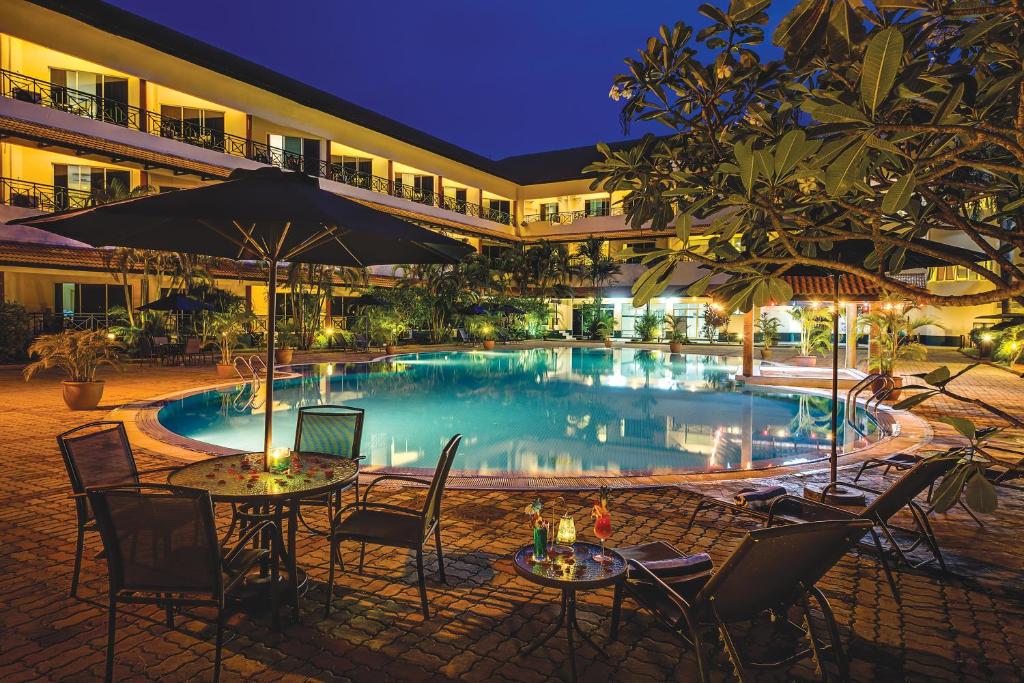 a pool with tables and chairs in front of a building at The Qamar Paka, Terengganu in Paka