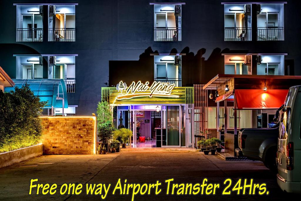 a building with a neon sign in front of it at Naiyang Place - Phuket Airport in Nai Yang Beach