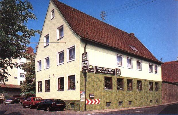 un bâtiment blanc avec un toit rouge dans une rue dans l'établissement Gasthof Wiesneth, à Pommersfelden