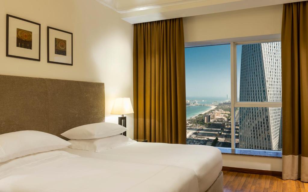 a hotel room with a bed and a large window at Grosvenor House, a Luxury Collection Hotel, Dubai in Dubai
