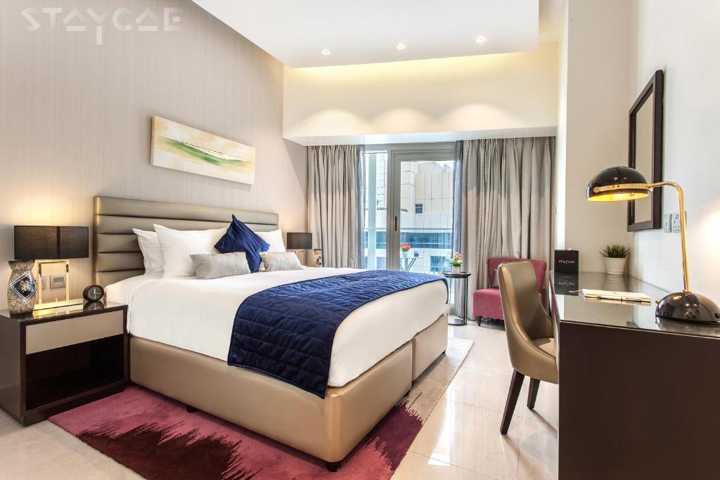 a hotel room with a bed and a desk and a desk at Staycae Holiday Homes - Majestine in Dubai