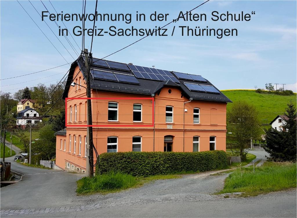 une maison avec des panneaux solaires en haut dans l'établissement Ferienwohnung West - Alte Schule Sachswitz, à Greiz