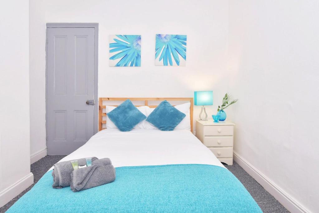 a bedroom with a large bed with blue pillows at Townhouse @ Hanley Road Stoke in Ford Green